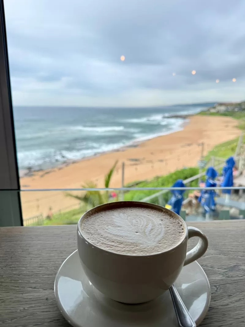 Latte-art cappuccino with a Ballito beach view